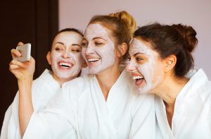 Three young happy women with face masks at spa resort.